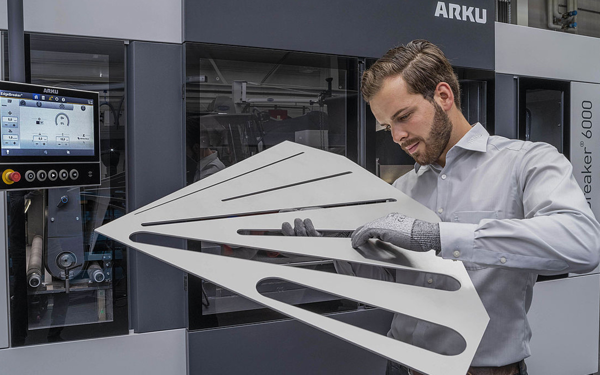 Man with large laser part in front of deburring machine